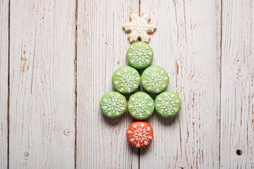 Christmas tree made from green macarons with snowflake icing decorations with snowflake sugar cookie tree topper  on a white weathered wooden table background with copy space and room for text.