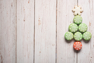 Christmas tree made from green macarons with snowflake icing decorations with snowflake sugar cookie tree topper  on a white weathered wooden table background with copy space and room for text.