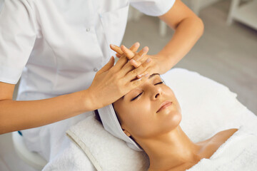 Facial massage. The beautician does an anti-aging face massage with his hands in a cosmetology clinic