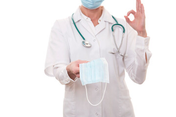 Young doctor in white uniform and stethoscope wearing mask and showing ok sign on isolated background