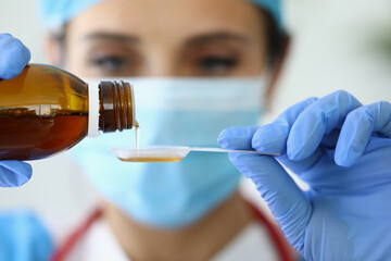 Doctor pours medicine into measuring spoon. Medicines for diseases concept