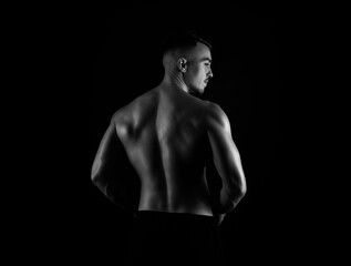 Fototapeta na wymiar Muscular male torso of fit bodybuilder on black background in black and white