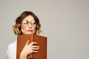 woman with notepad in hands business work beige background glasses hairstyle