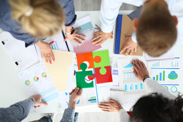 Businesspeople at table with business indicators and colored puzzles. Business building effective work concept