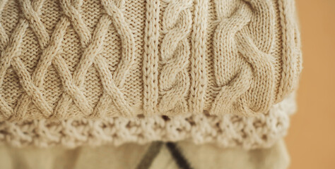 Top view of a stack of neatly folded white warm patterned sweaters prepared for the cold weather. Cold weather clothing.