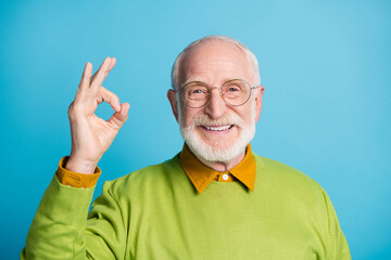 Photo of retired grandpa raise hand fingers showing okey smile wear specs green sweater isolated...