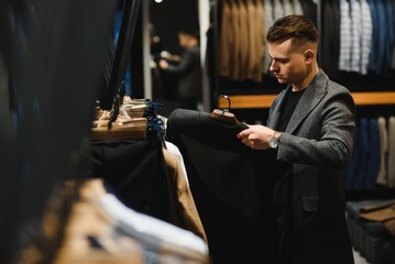 client is an elegant guy looking at the price tag of a suit jacket in a classic costume store on a hanger.