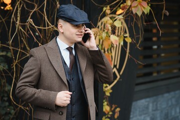A man posing in the image of an English retro gangster of the 1920s dressed in Peaky blinders style...