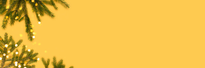 Banner with fir branches and glowing bokeh on a yellow background. Christmas concept.