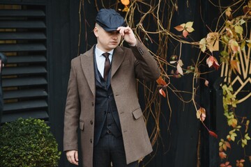 A man posing in the image of an English retro gangster of the 1920s dressed in Peaky blinders style...