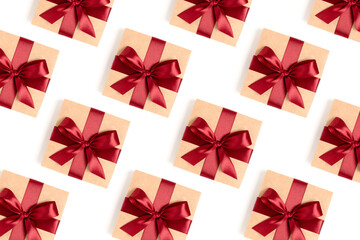 Repetitive pattern made of gift boxes tied with red ribbons on a white background. Holdays backdrop.