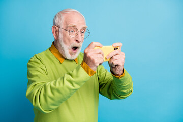 Profile photo of crazy grandfather hold smartphone open mouth wear eyewear green pullover isolated blue color background © deagreez