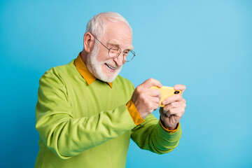 Profile photo of excited grandpa hold cellphone cheerful smiling wear eyeglasses green sweater isolated blue color background