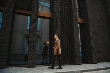 Portrait of handsome fashion businessman model dressed in elegant suit. Man posing on street background. Metrosexual