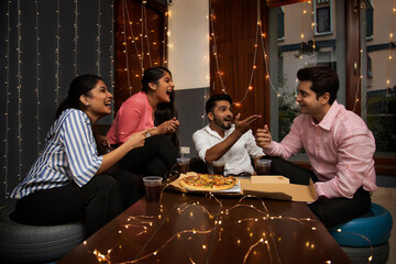 THREE FRIENDS LOOKING AT ANOTHER FRIEND AND PLAYFULLY TEASING WHILE CELEBRATING	