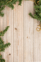 Christmas composition. Fir branches with gold decorations on a wooden vertical background.