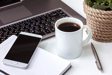 Desktop at home laptop open Notepad with pen coffee Cup on white table