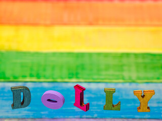 lettering dolly on wood vintage plank background in lgbt flag colors