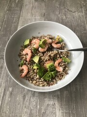 Red and white quinoa with fresh prawns and avocado against a wooden background