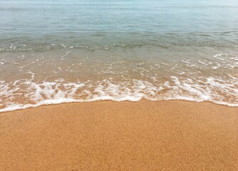 Soft wave of blue ocean on sandy beach background.