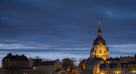 Fototapeta premium Morning view over the district Södermalm with old houses and the church Katarina kyrka at sunrise with background sunlight and town lights.