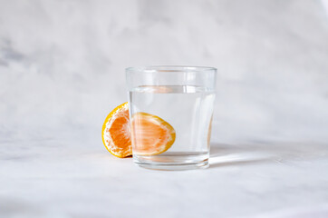 Mandarin citrus fruits reflecting through a glass cup with water on a gray background. Distorted water image. Art concept. Minimalism. Copy space. Abstraction. Perspective, fractured and skewed images