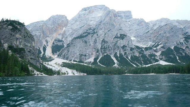 Lake Braies shot slow motion from a rowing boat, beautiful movement on the water with the distant huge mountains in the background, Italy.