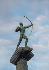 100 year old monumental statue of a archer and an eagle at a blue sky background on the island Djurgården in Stockholm