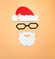 paper, red Santa Claus hat with a white beard on a beige background, top view