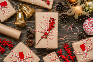 Top view of decorated christmas presents, baubles in box, golden bells, twine string, holly berry,...