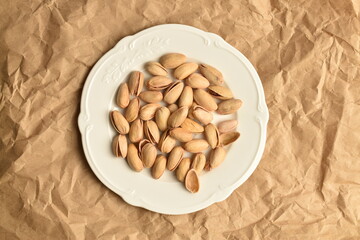 Organic salted pistachios, close-up, on brown paper.
