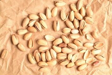 Organic salted pistachios, close-up, on brown paper.