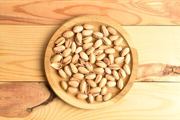Organic salted pistachios, close-up, on a wooden table.