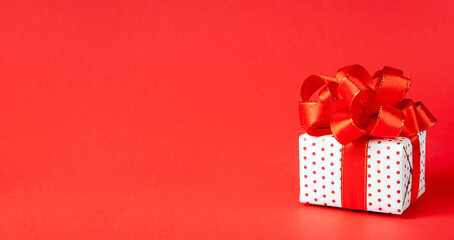 Banner a festive gift with a ribbon on a red background with a place for your text. concept for new year, christmas, valentine's day,