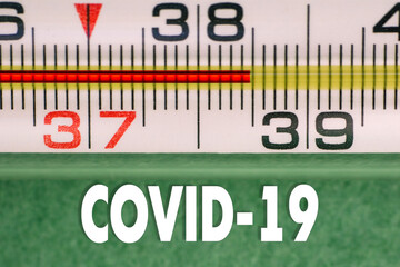 Close up of high temperature thermometer with COVID-19 text. Signs of coronavirus disease. Viral symptoms. Body temperature checks