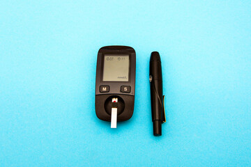 Diabetes test with Copy space . Blood sugar test isolated on blue background. Glucose meter with blood sugar level. Medicine, diabetes, glycemia, health care concept.