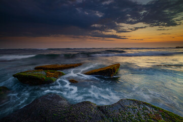 Obraz premium Amazing seascape with motion waves. Waterscape background. Moving water. Nature concept. Sunset scenery background. Long exposure. Mengening beach, Bali, Indonesia.