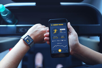 Sport woman running treadmill use smartwatch connect smartphone workout app and listening music. Indoors gym background.