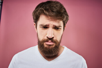 Obraz premium bearded man in white t-shirt emotions displeased facial expression studio pink background