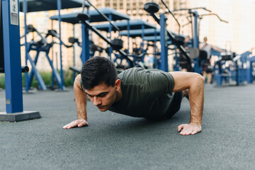 Young man doing push ups outdoor. Young handsome runner warming up and doing some push ups as part of his training. Action and healthy lifestyle concept