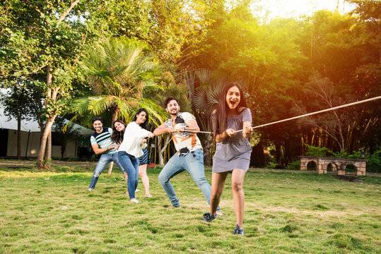 Indian asian young friends playing tug of war or rassi khech outdoors