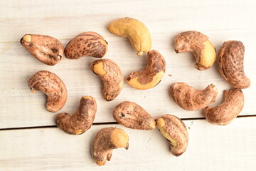 Fragrant fried salted cashews, close-up, on a white wooden table.