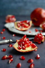 Close up of slices of ripe red pomegranate on a dark background. Vertical