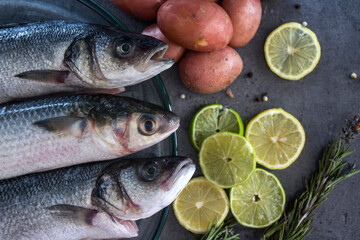 Fish and chips ingredients on a table. Raw fish, fresh potatoes, lemon and rosemary top view. Healthy eating concept. 