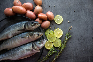 Fish and chips ingredients on a table. Raw fish, fresh potatoes, lemon and rosemary top view. Healthy eating concept. 