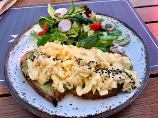Scrambled Egg with Avocado Smash on Bread and Salad for Breakfast.