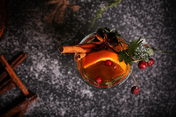 mulled wine tea with cinnamon and orange stands on a dark background	