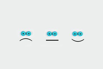 Imagen conceptual con tres caras gesticulando emociones sobre un fondo gris claro. Vista superior. Copy space