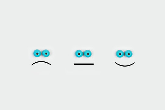 Imagen conceptual con tres caras gesticulando emociones sobre un fondo gris claro. Vista superior. Copy space