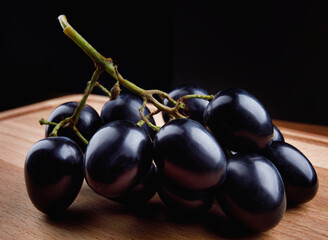 A small bunch of black grapes on a wooden board.